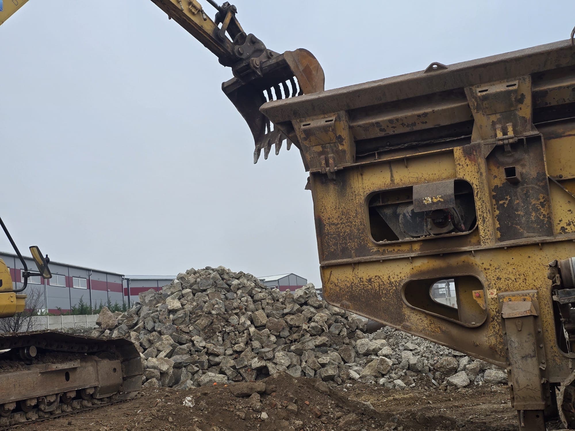 Excavator alimentand concasorul cu beton spart